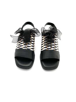 Sandalias negras con estampado blanco y negro, detalles naranjas y lazos negros transparentes.