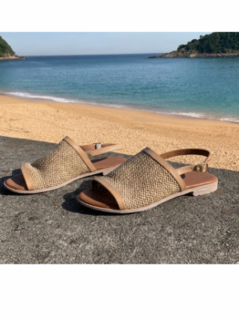 Sandalias planas beige con tejido tipo rafia, punta abierta y correa ajustable en el talón.